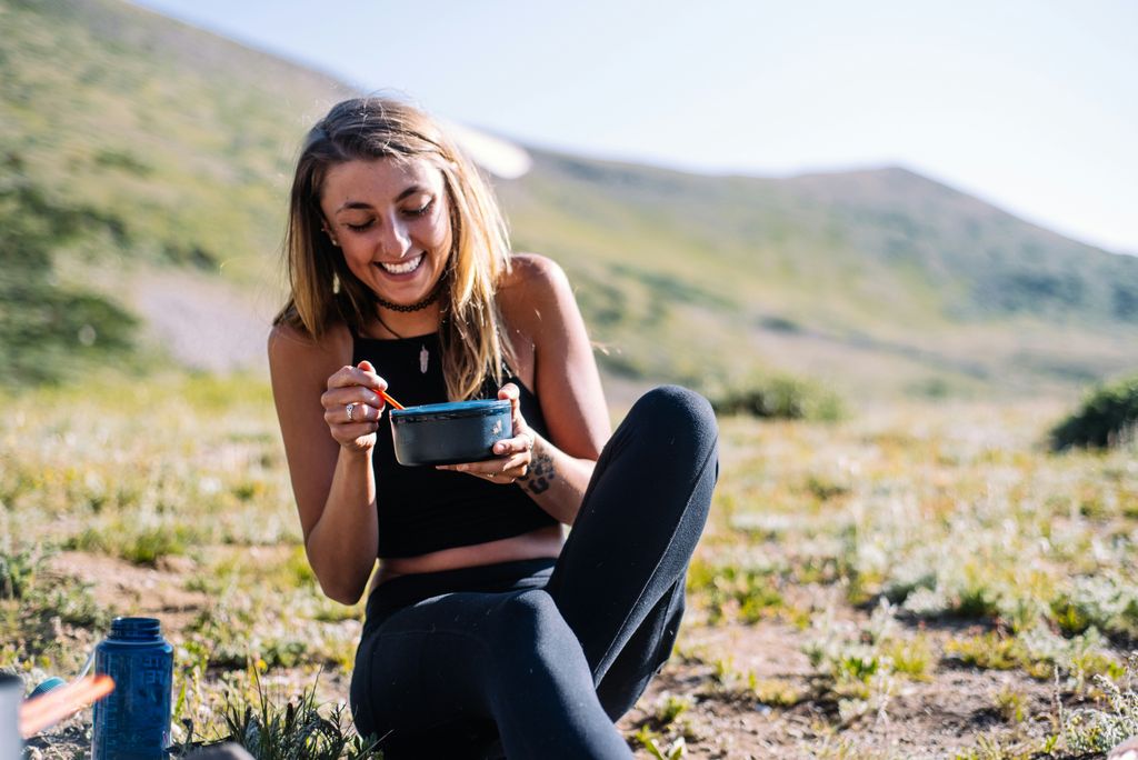 Chica comiendo, con paisaje de fondo