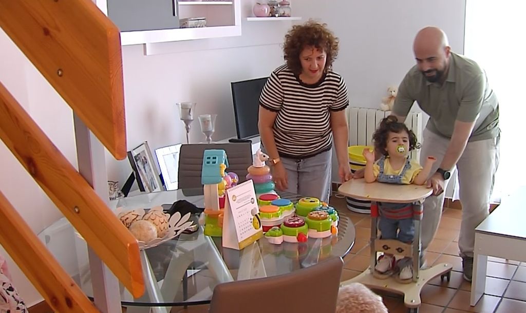 Carla en el andador junto a sus padres.