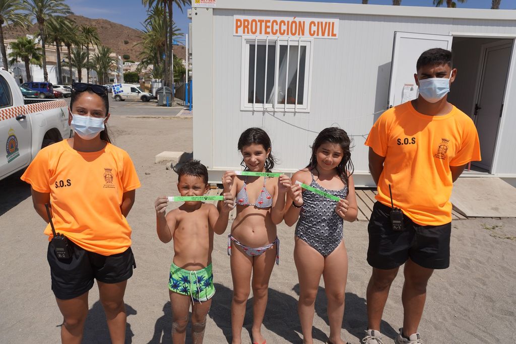 Miembros de protección civil con los niños con sus pulseras en Carboneras, Almería.