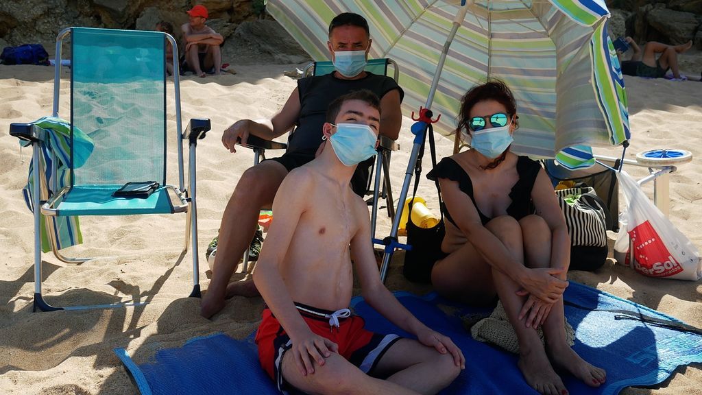 Una familia en la playa, con sus mascarillas