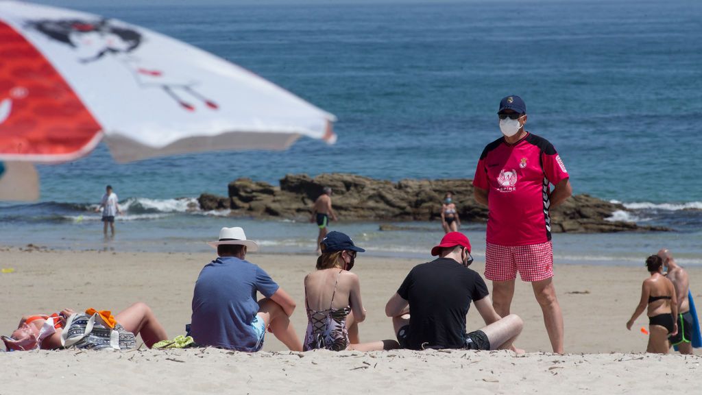 EuropaPress_3228427_varias_personas_protegidas_mascarillas_toman_sol_playa_rapadoira_foz