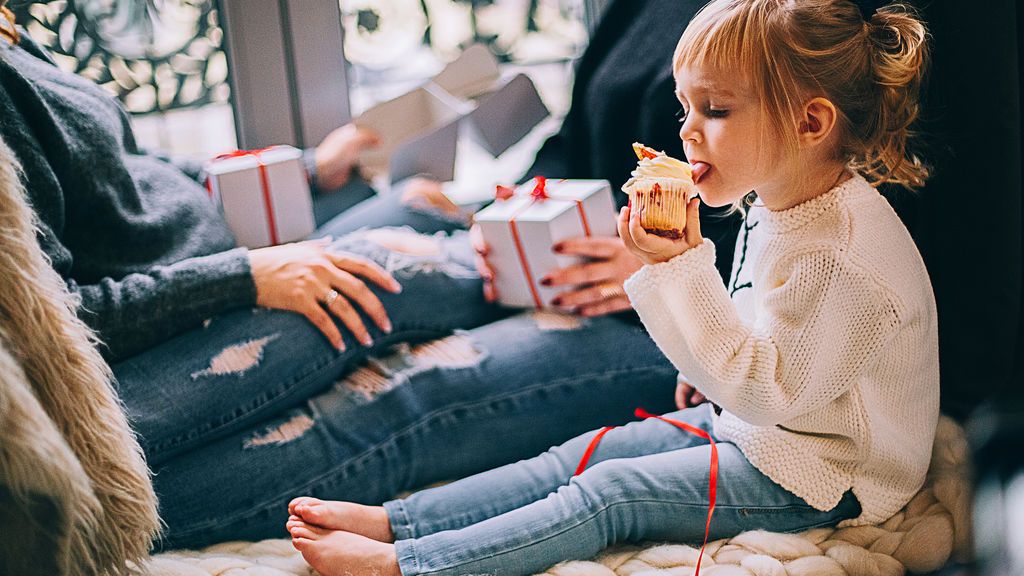 girl-eating-cupcake-while-sitting-beside-woman-in-blue-denim-1261408