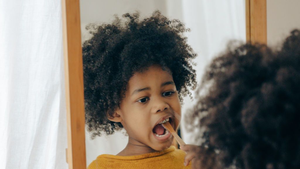 african-american-kid-brushing-teeth-in-front-of-mirror-4546133