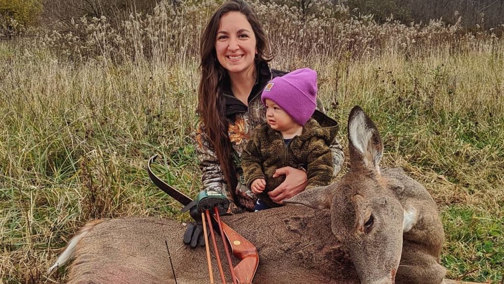 Beka Garris posando con un ciervo muerto y su hija de dos años