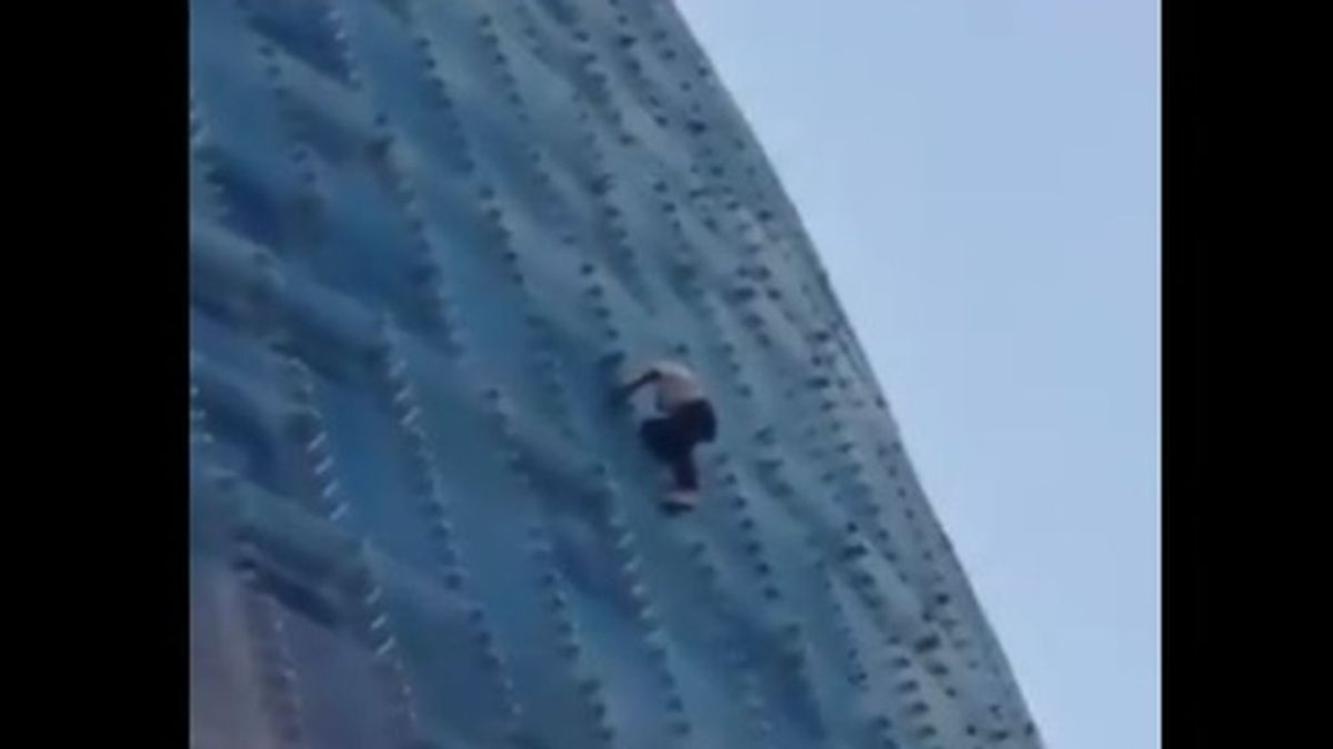 Un individuo intenta escalar sin ningún tipo de protección y descalzo la torre Agbar en Barcelona