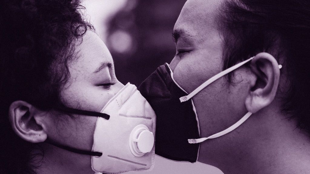 Una pareja se besa con mascarilla
