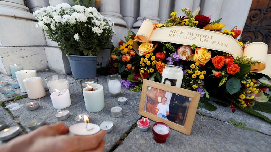 Una mujer pone una vela cerca de una foto de Vincent Loques, sacristán de la iglesia de Notre Dame, una de las víctimas