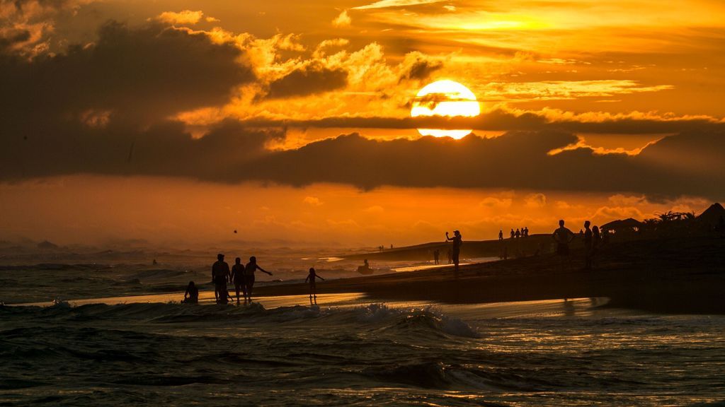 Turistas caminan junto al mar