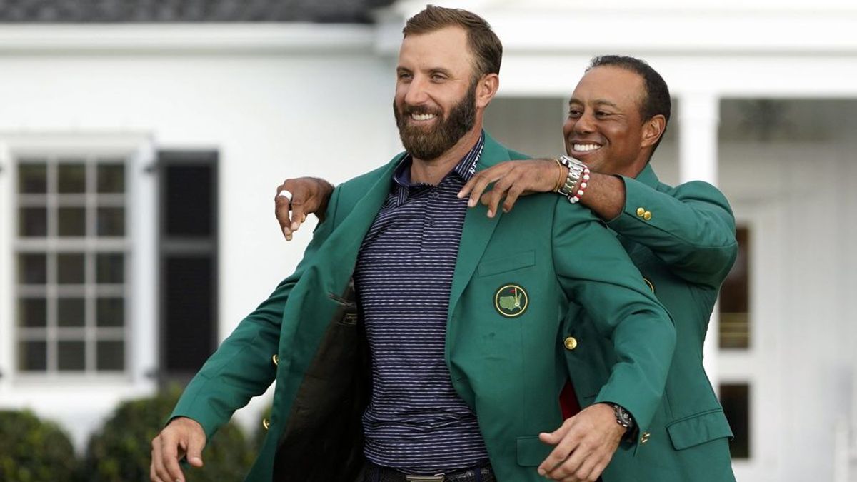 Tiger Woods pone a Dustin Johnson la chaqueta verde.