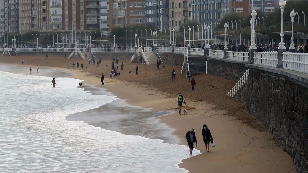 Varias personas pasean por la playa de San Lorenzo de Gijón
