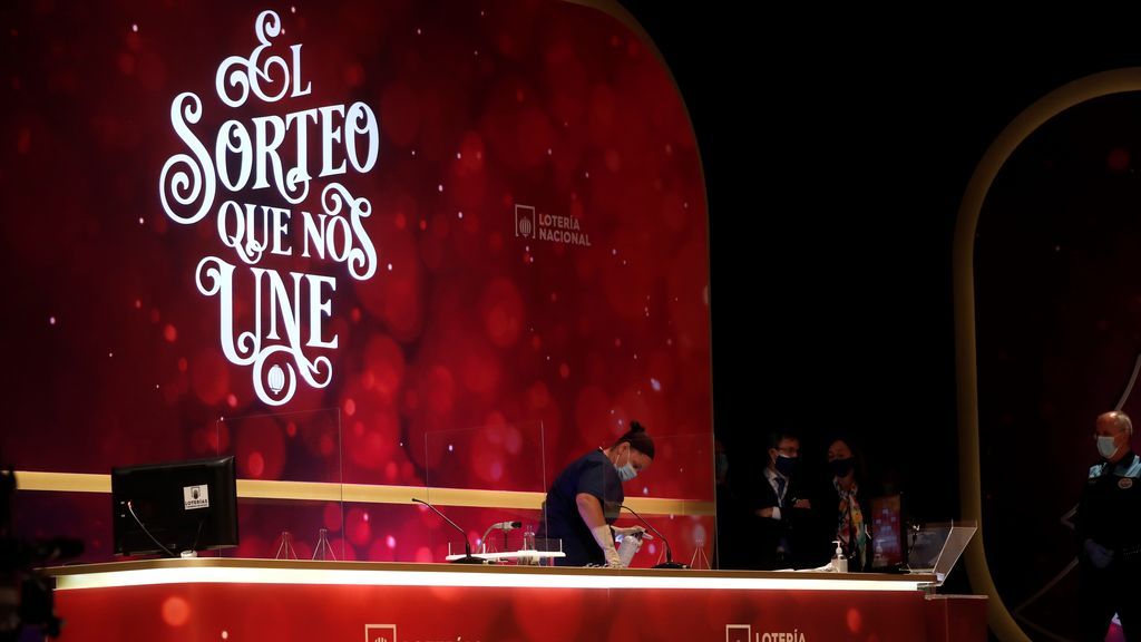 Una operaria del servicio de limpieza desinfecta los puestos de la presidencia durante el Sorteo