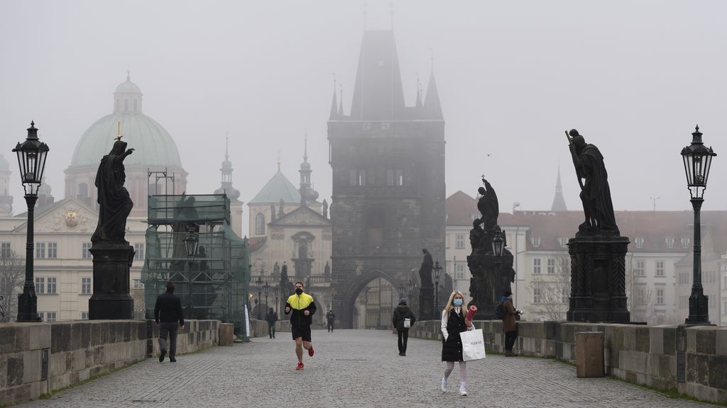 Personas con mascarilla recorriendo un puente de Praga