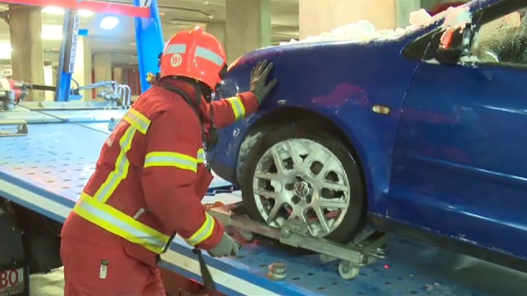 Operarios recogiendo coches abandonados por la nevada