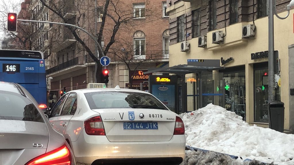 El autobús no puede circular por su carril, y los viajeros tienen que saltar la nieve para llegar a él, en plena calle Alcalá.