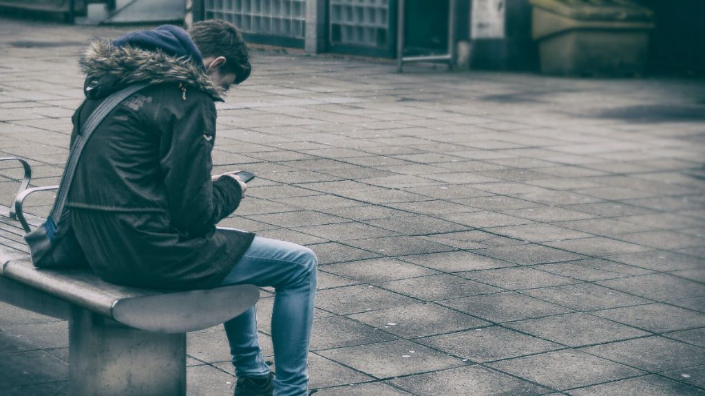 Un joven solo en el patio mirando el móvil