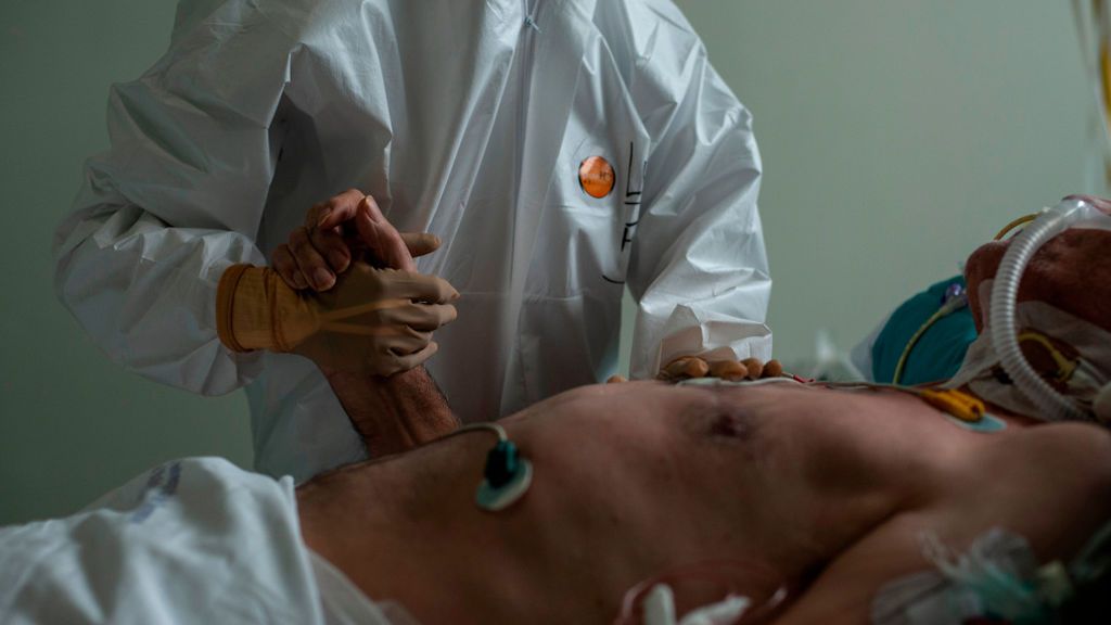Un sanitario del Complejo Hospitalario Universitario de Ourense coge la mano a un paciente.
