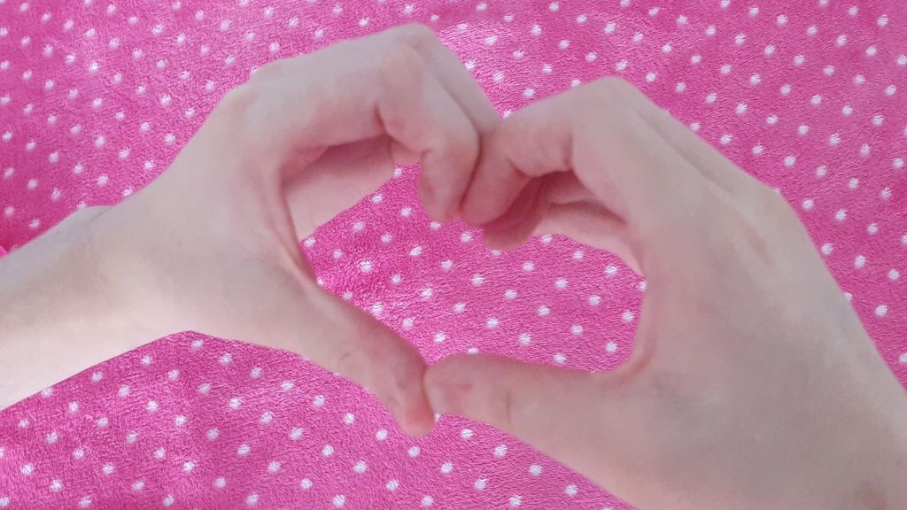 Sara, dibujando un corazón con sus manos
