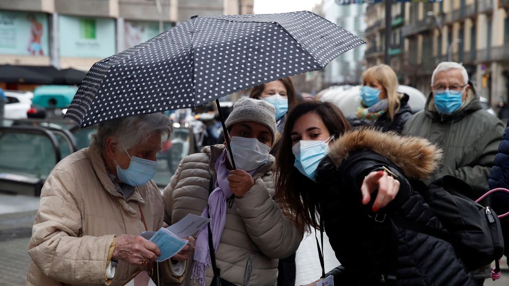 Varias votantes piden indicaciones a una empleada municipal mientras hacen cola ante un colegio electoral
