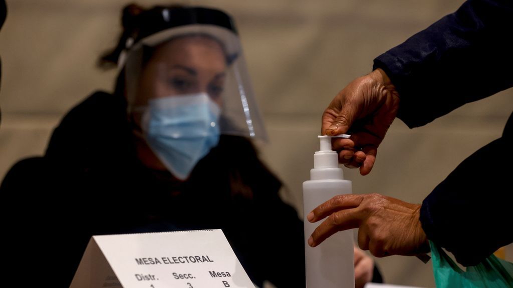 Una persona desinfecta sus manos con gel hidroalcohólico antes de depositar su voto en el polideportivo Can Ricart del barrio del Raval de Barcelona