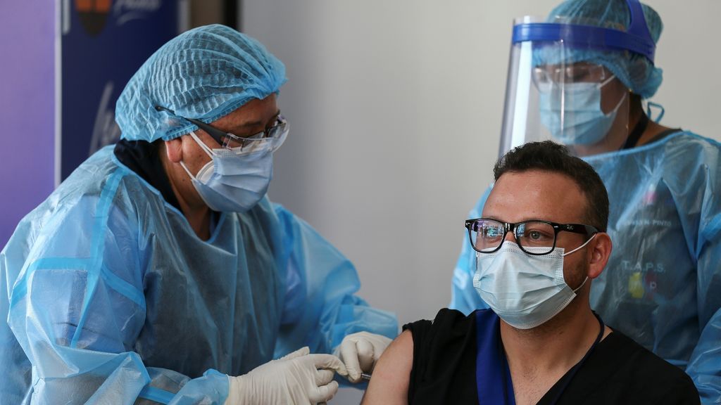 Sanitaria vacunando a un paciente