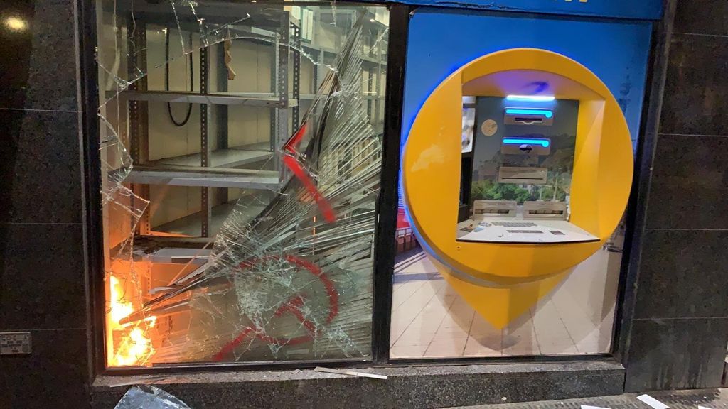 Sucursal bancaria en llamas destrozada por un grupo de manifestantes
