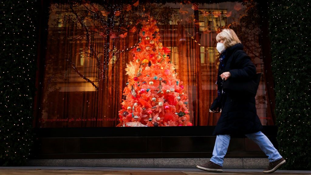 Una mujer con mascarilla pasea junto al árbol de Navidad de un establecimiento