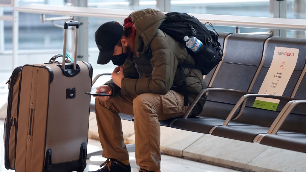 Un joven se sienta en un banco del aeropuerto de Madrid