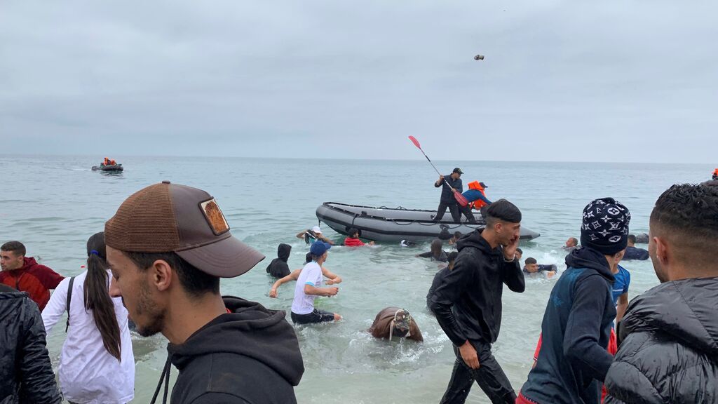 Un grupo de personas se hacen con una embarcación de las autoridades marroquíes en la playa de la localidad de Fnideq
