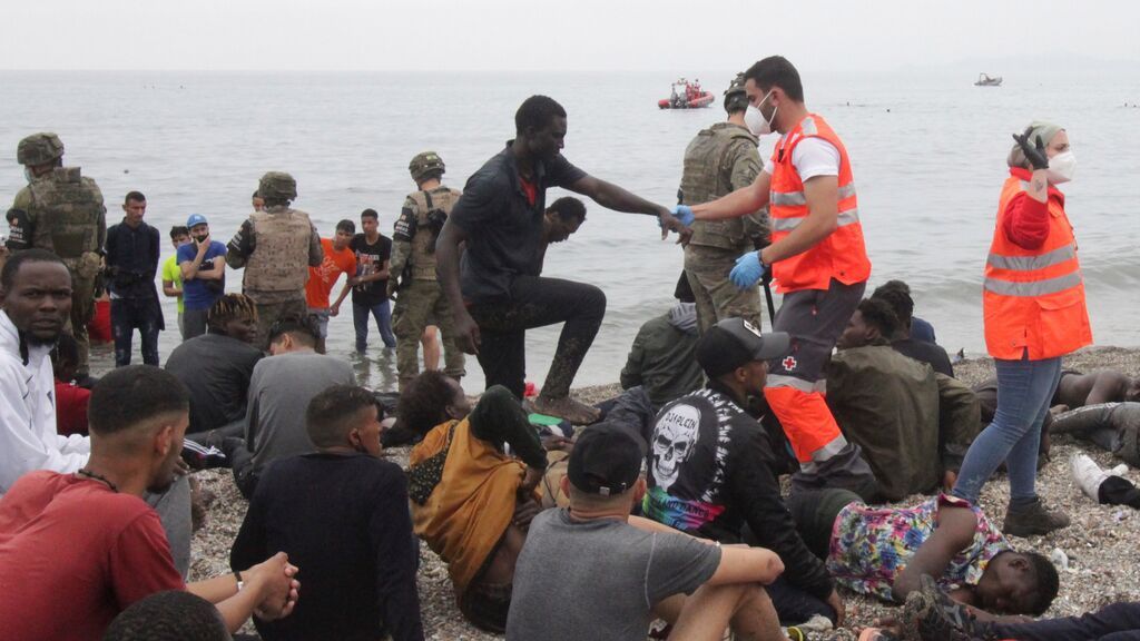 Miembros del Ejército de Tierra y de la Cruz Roja ayudan a un grupo de inmigrantes