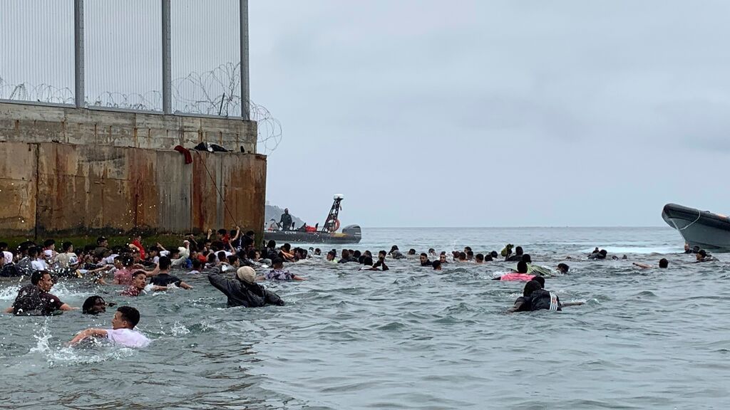 Un grupo de personas tratan de llegar a nado desde la playa de la localidad de Fnideq