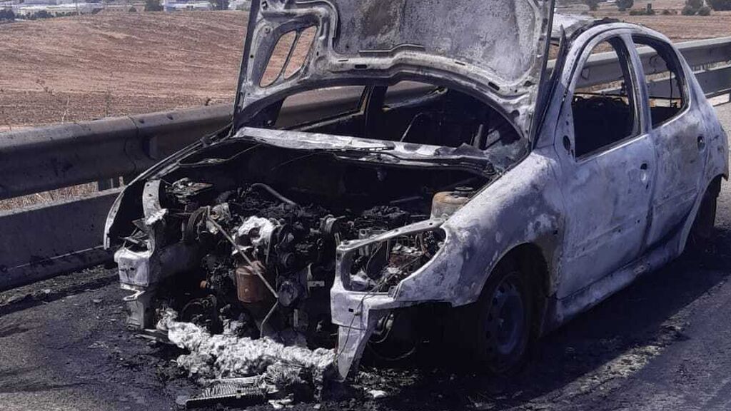 Un coche incendiado en una carretera