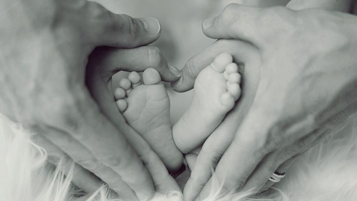 Los pies de un bebé sostenidos por las manos de sus progenitores