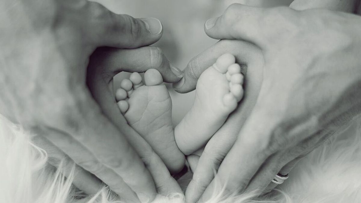 Los pies de un bebé sostenidos por las manos de sus progenitores Los pies de un bebé sostenidos por las manos de sus progenitores