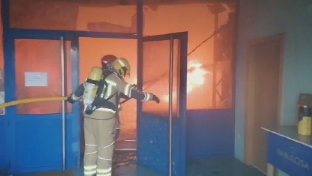 El difícil trabajo de los bomberos en la extinción del fuego que afecta a una nave industrial de Cervo