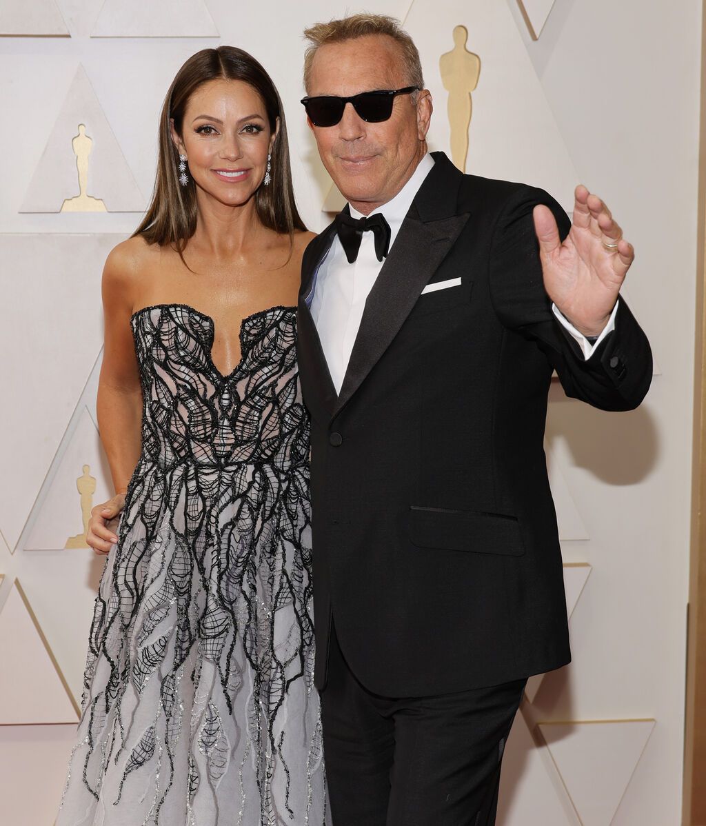 Christine Baumgartner y Kevin Costner posan en la alfombra roja de los Premios Oscar 2022