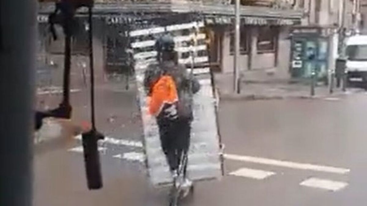 Un hombre se pasea por Zaragoza con un somier subido en un patinete