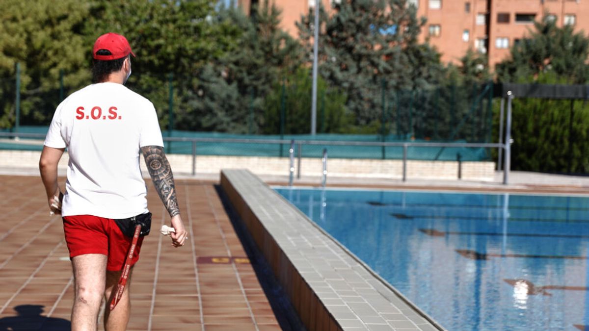 Un socorrista camina por las instalaciones de una piscina Un socorrista camina por las instalaciones de una piscina