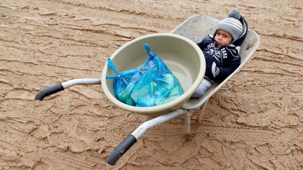 Un niño se sienta en una carretilla en el campo de Khazer