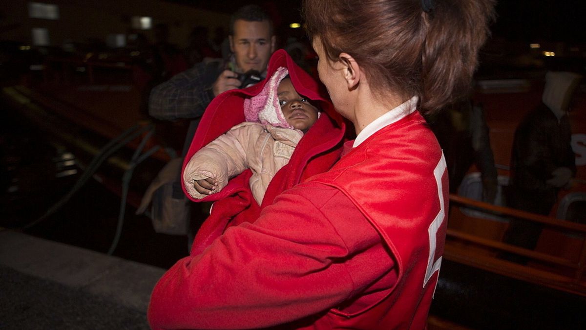 Una integrante de la cruz roja arropa al bebe que viajaba en una de las pateras rescatadas
