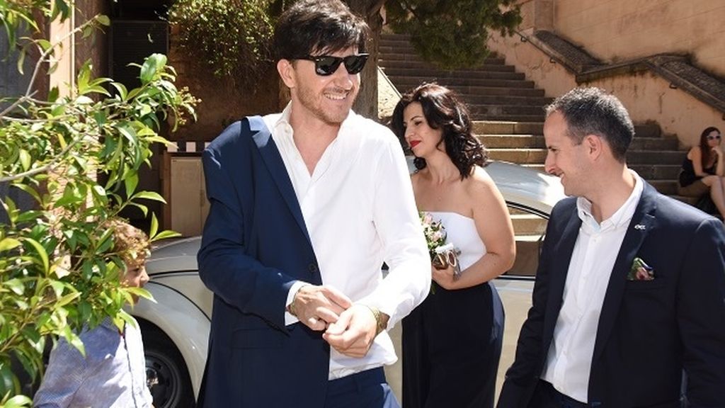 Los novios, en un antiguo escarabajo de color blanco decorado con flores de paniculata