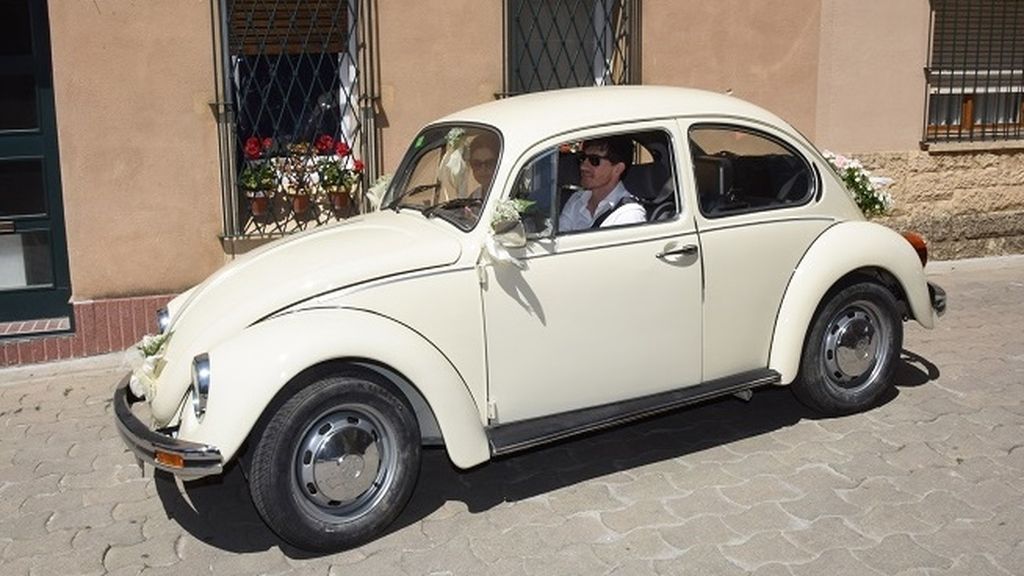 Los novios, en un antiguo escarabajo de color blanco decorado con flores de paniculata