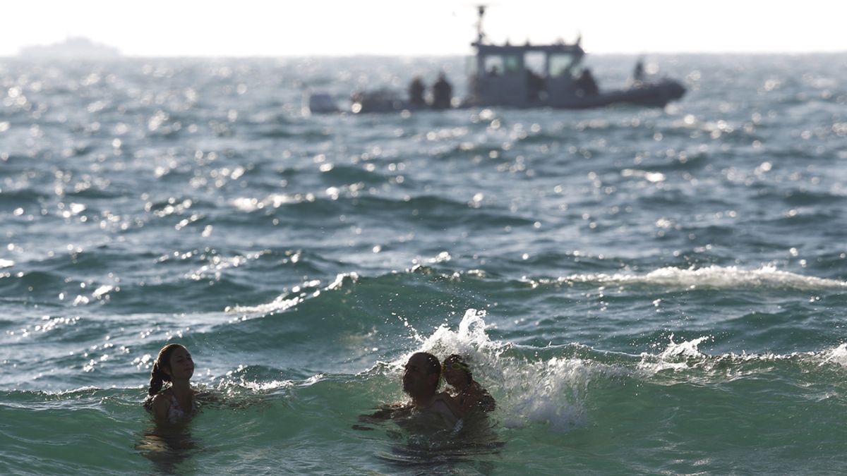 Israelíes se bañan en la playa frente a una patrulla israelí