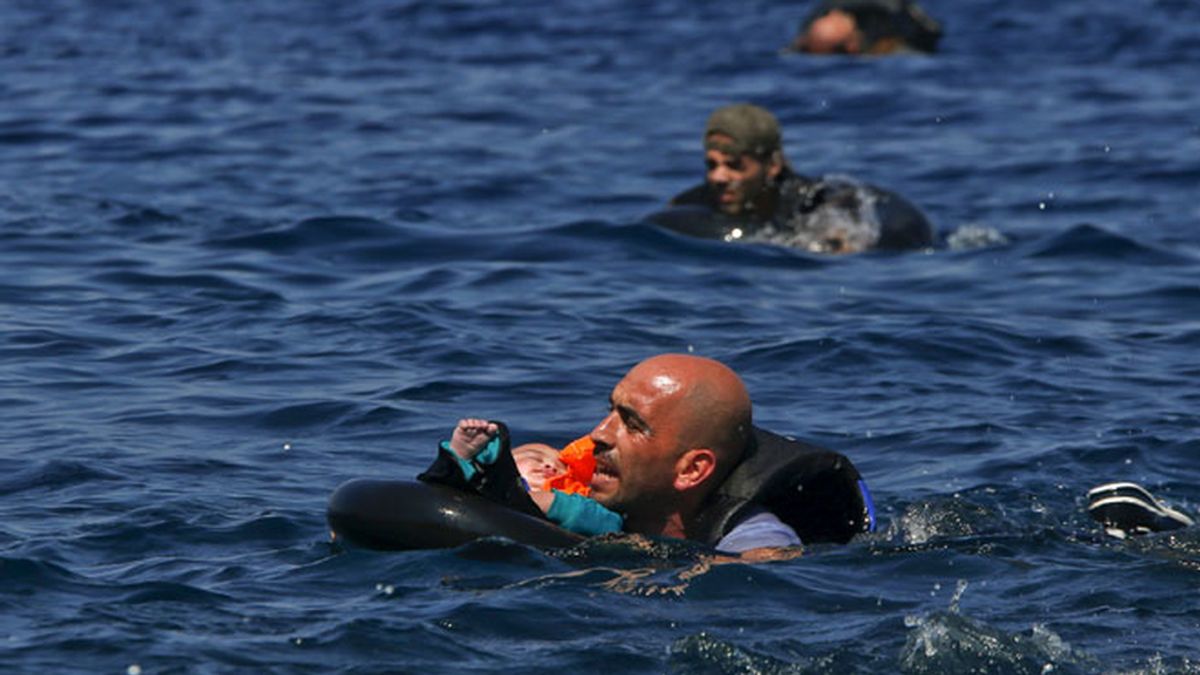 Llegada de refugiados a Lesbos. Un hombre sujeta a un bebé.