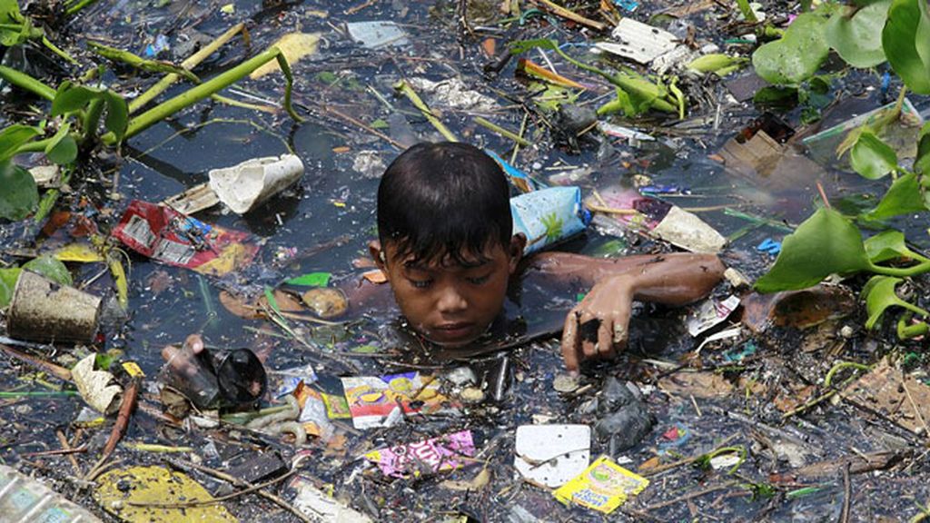 Niños filipinos nadando entre basura para sobrevivir