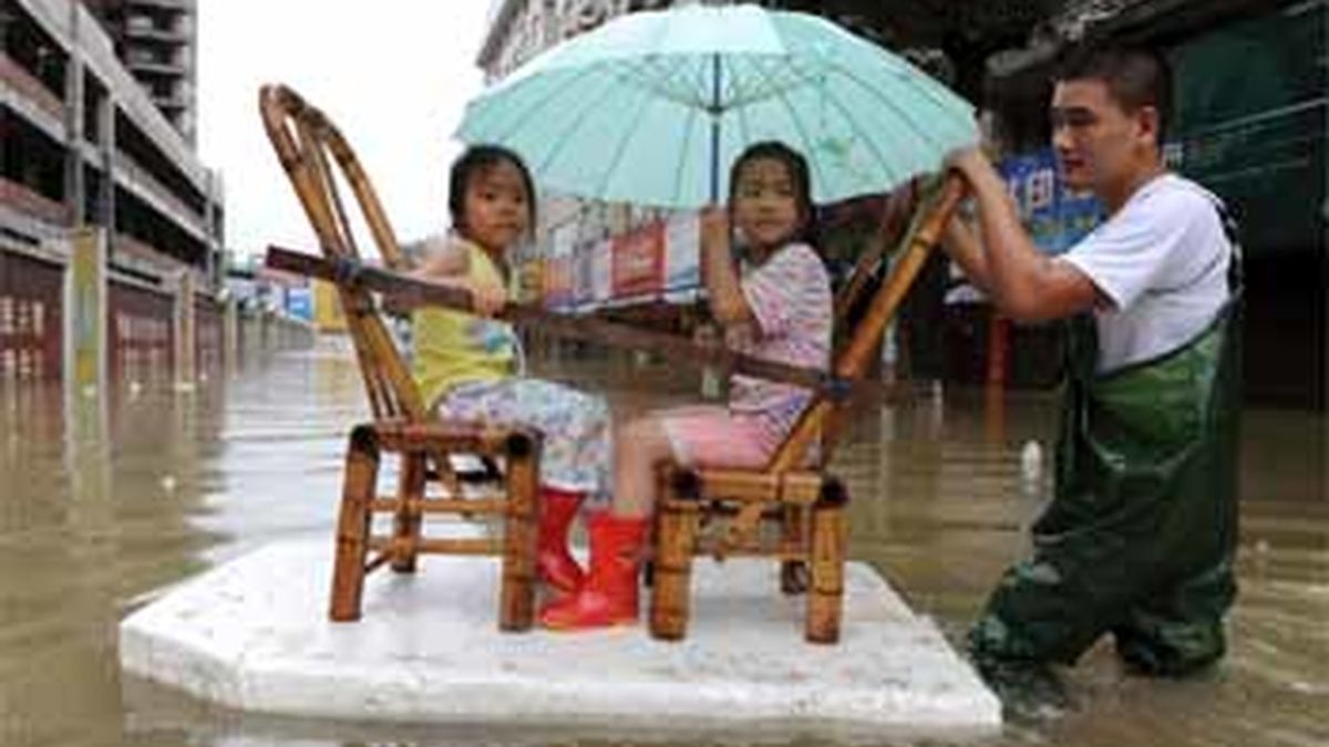 Un hombre tira de una balsa improvisada para transportar a dos niñas tras el tifón 'Morakot', en China