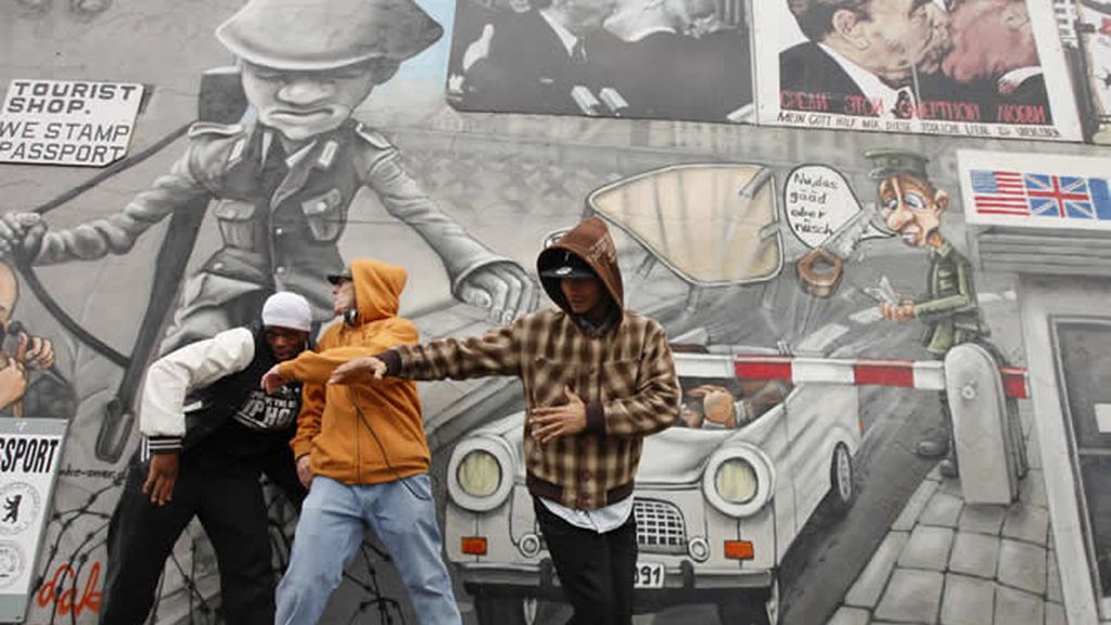 Baile callejero frente a pinturas políticas en el muro