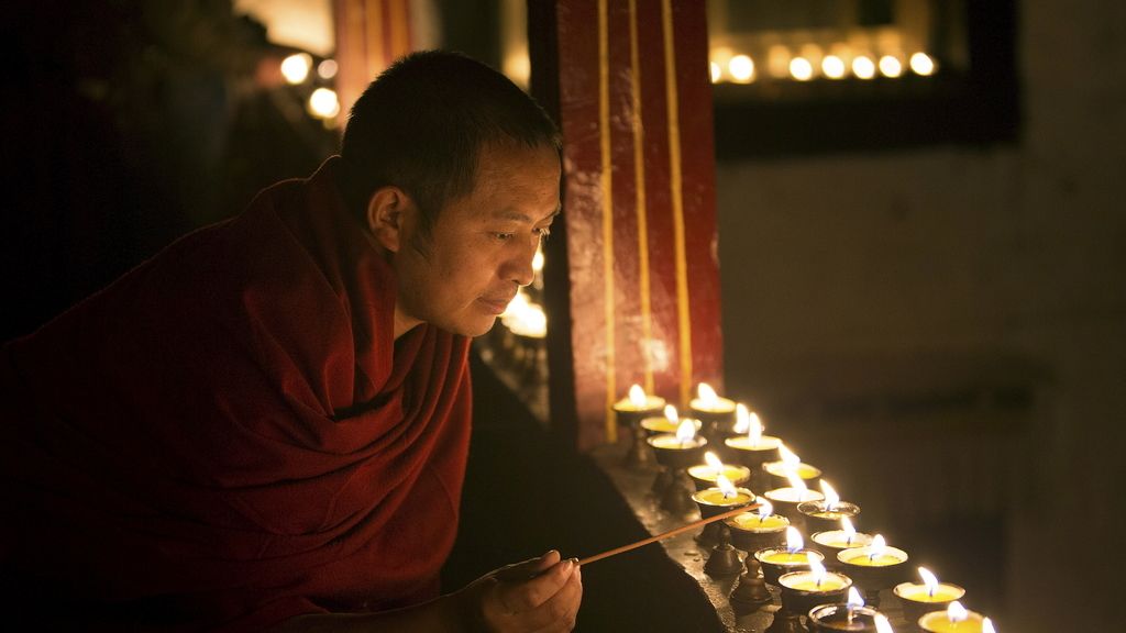 Un monje tibetano enciende una lámpara en el templo de Lhasa