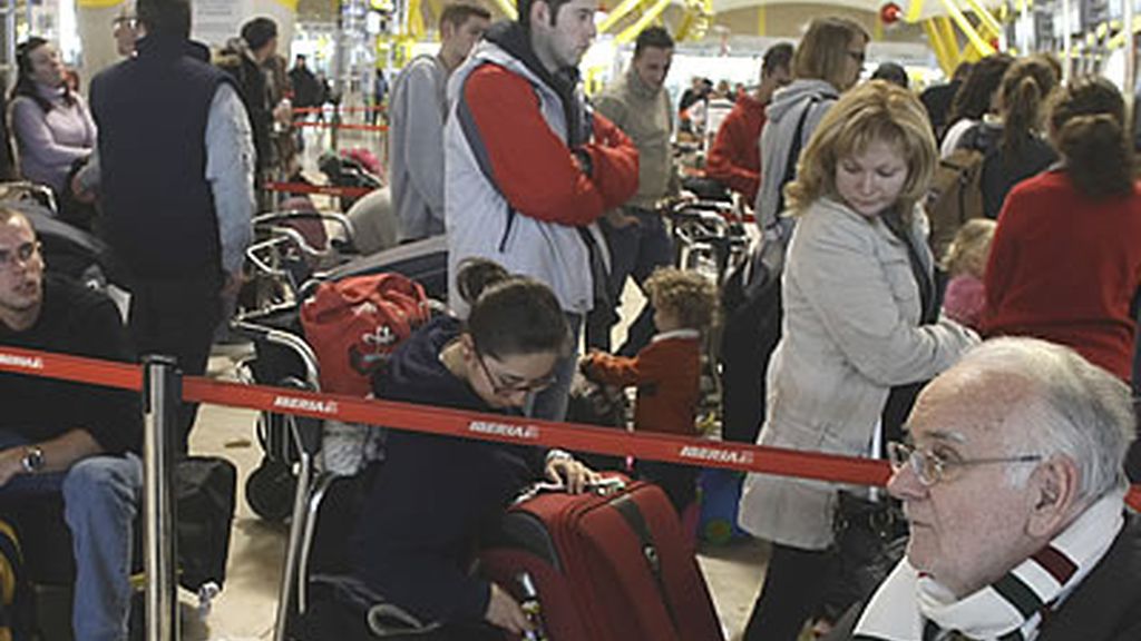 Un grupo de frustrados viajeros espera una larga cola en el madrileño aeropuerto de Barajas