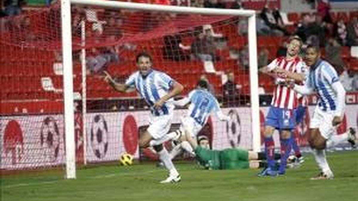 El defensa brasileño del Málaga, Weligton Robson (i), celebra ante el centrocampista uruguayo del Sporting, Sebastián Eguren (c), el gol conseguido por Robson, el primero para el conjunto durante el partido correspondiente a la decimo séptima jornada de la Liga en Primera División que ambos equipos jugaron en el estadio asturiano de El Molinón. EFE
