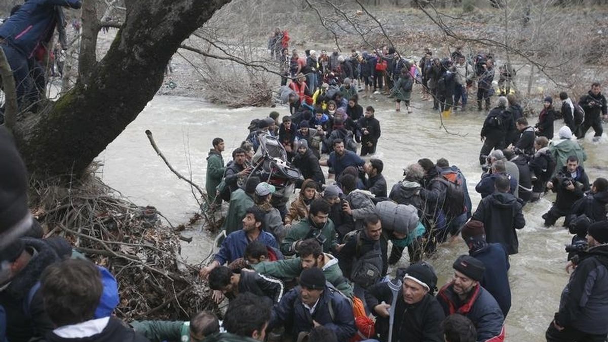 Un grupo de refugiados cruza un río cerca del campamento de Idomeni para intentar entrar en Macedonia